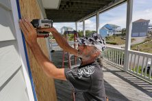 A man boards up his windows at his home.
