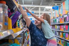A father holds his daughter as they reach for school supplies at Walmart.