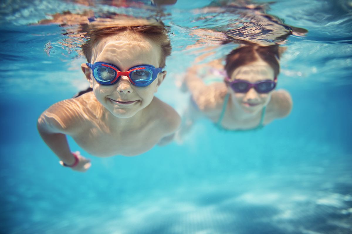 happy little children with goggles swim underwater.
