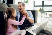 A man arm wrestles his daughter.