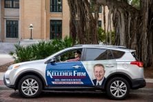 A driver sits in his car, which is wrapped with advertising.