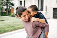 A woman carries her son on her back.