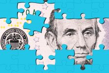 Blue puzzle pieces are scattered over money with Abraham Lincoln's face on it.