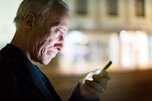 A man makes an unhappy expression while staring at his phone at night.