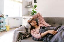 A woman lays on her couch while being sick.