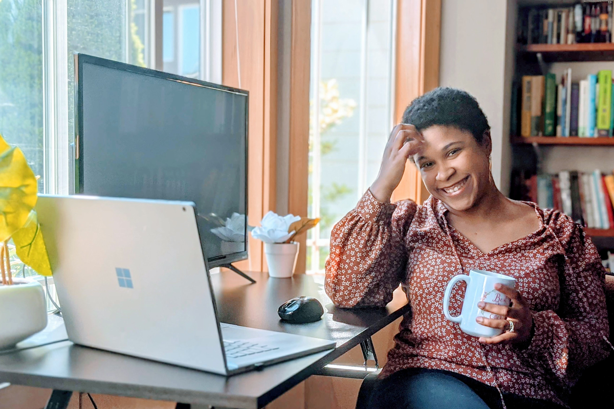 A woman smiles while sitting at her desk at home.