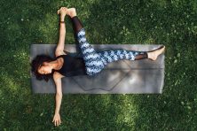 A woman does yoga in a patch of grass at a park.