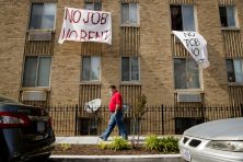 A man wearing a red shirt walks past signs saying,