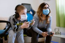 A boy plays video games with his babysitter.