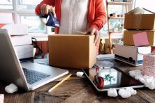 A woman tapes a box closed.