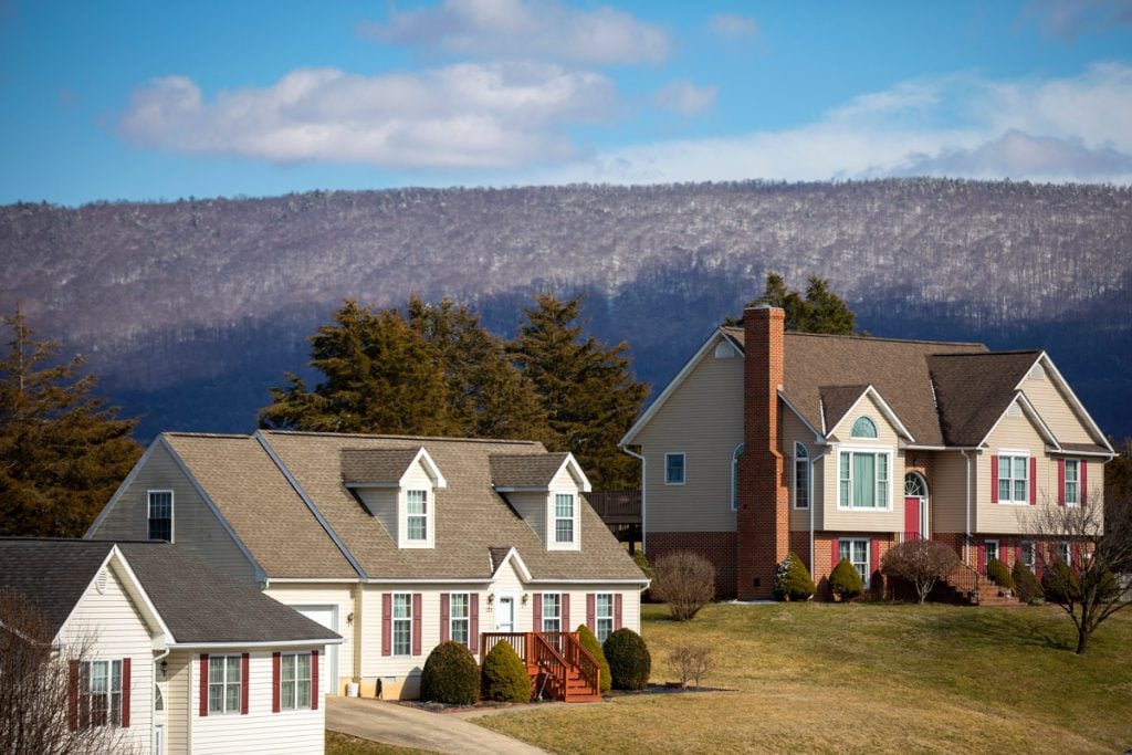 A row of houses sit on a hill with a mountain behind it.