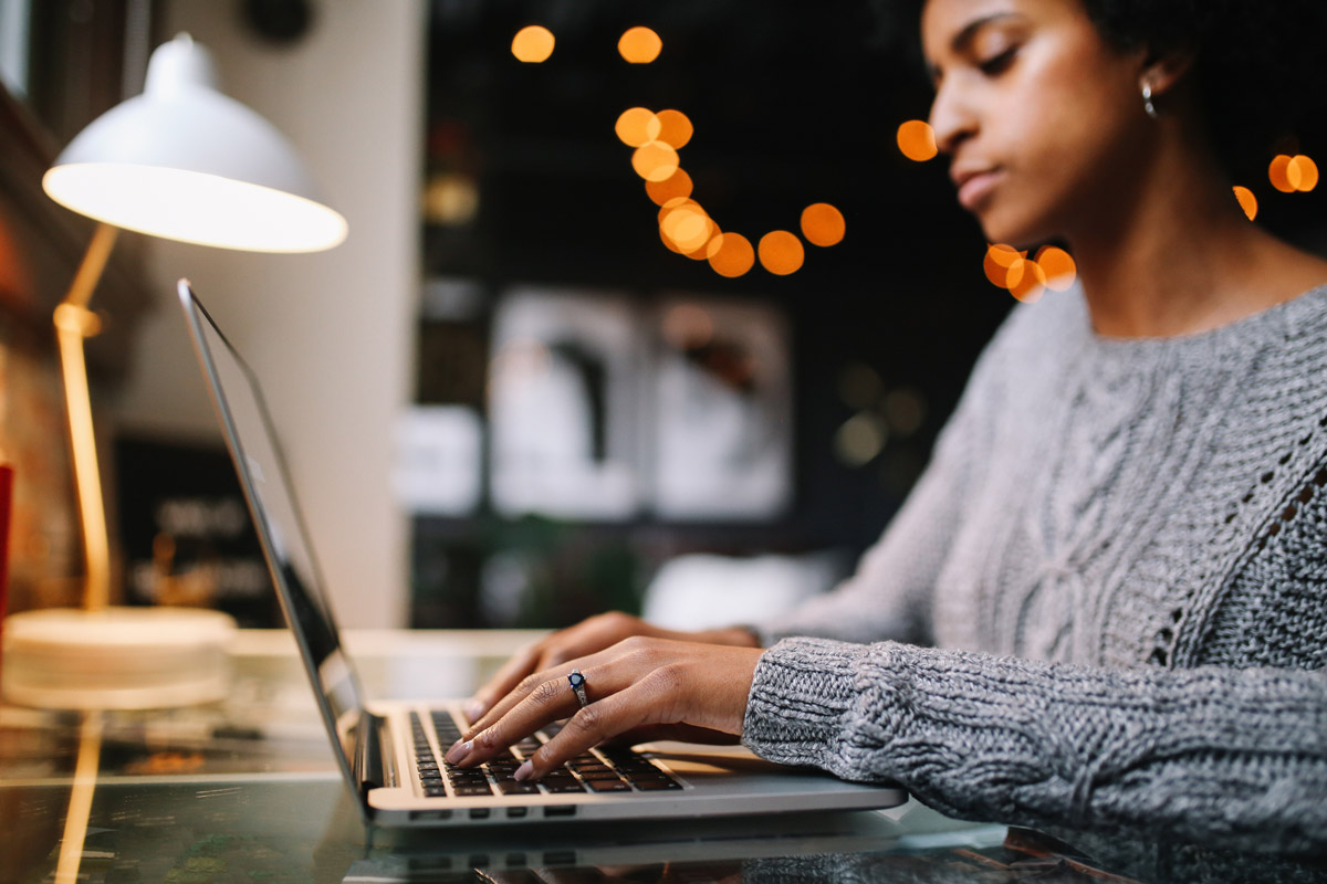 A woman types on her laptop at home. 