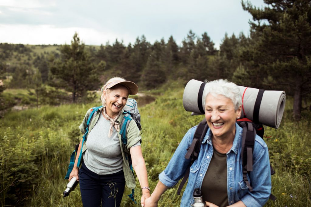 A lesbian couple hike together. This photo is meant to represent taking social security out based on your spouse.