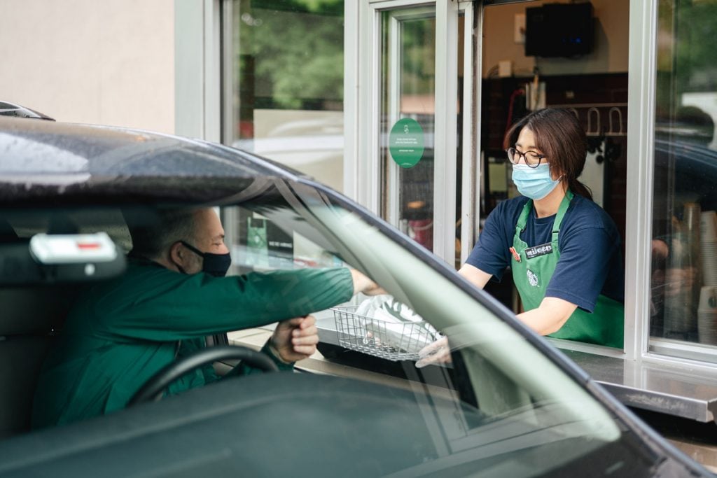 A Starbucks employees gives an order to a customer in the drive-thru. 