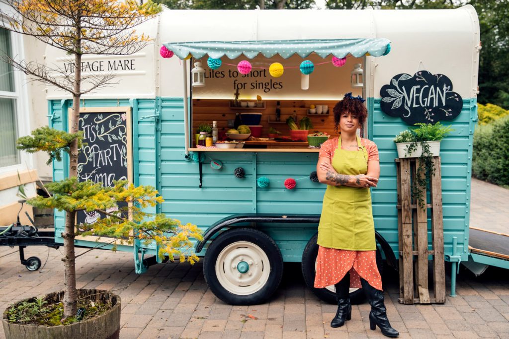 A vegan food truck owner stands in front of her food truck. This part of the story shows you how to search for your own bank promotions.