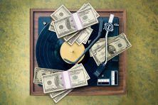 Money sits on top of a record in a record player.