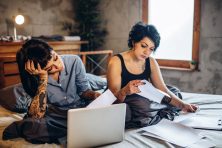 A couple sit in bed as they look over their finances.