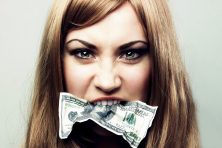 A woman holds a $100 bill in her mouth.