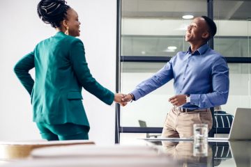 Two business professionals shake each other hands during a job interview.