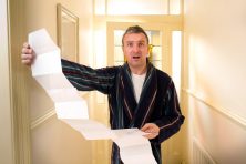 A man dressed in a robe looks worried as he looks at his massive bill.