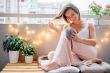 A woman drinks coffee on her backyard patio.