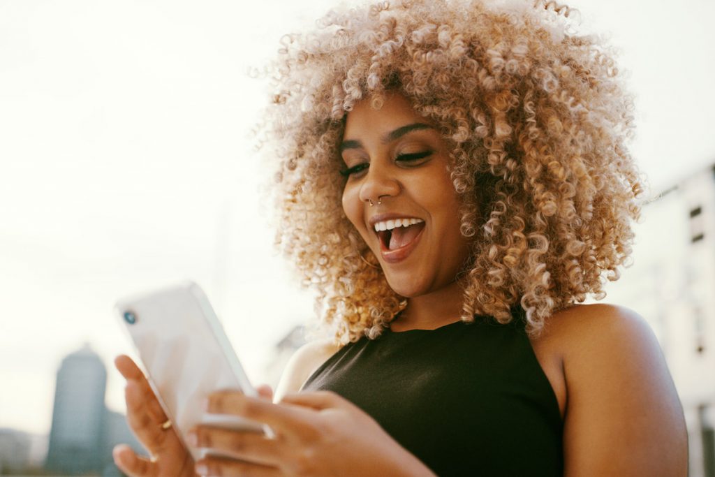 A woman looks surprised as she looks at her phone.