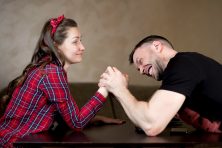 A man tries to get a woman&rsquo;s hand down while arm wrestling. The woman is stronger than the man.