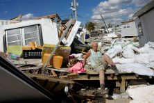 A woman climbs over debris after Hurricane Ian destroyed her trailer.