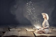 A woman sits on open books as the letters come to life she's typing on her laptop.