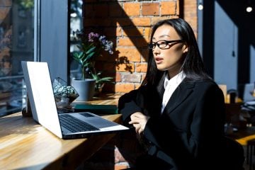 A woman works remotely from a coffee shop.