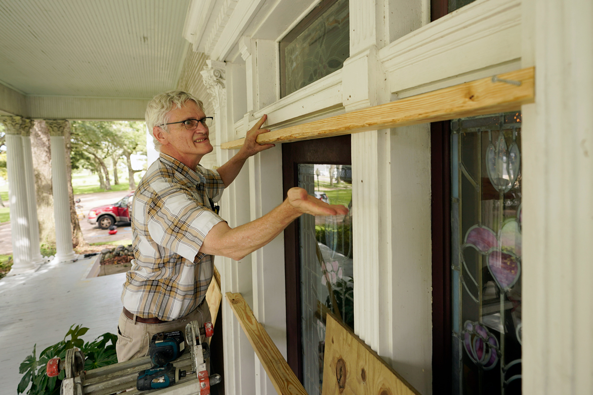 A man boards up the windows in the front of his home in preparation of a hurricane. 