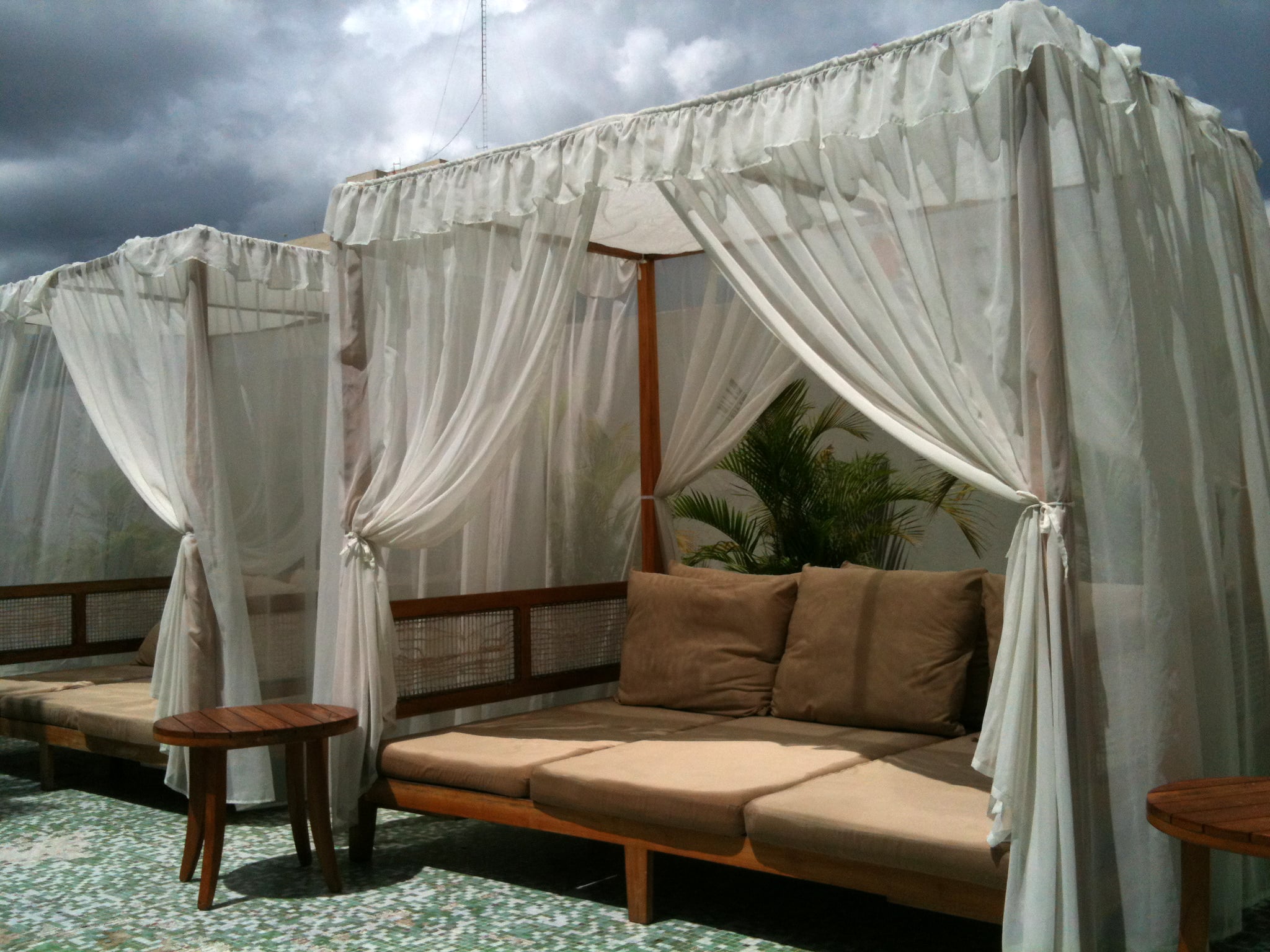 Outdoor curtains surround an outdoor couch to create privacy. 