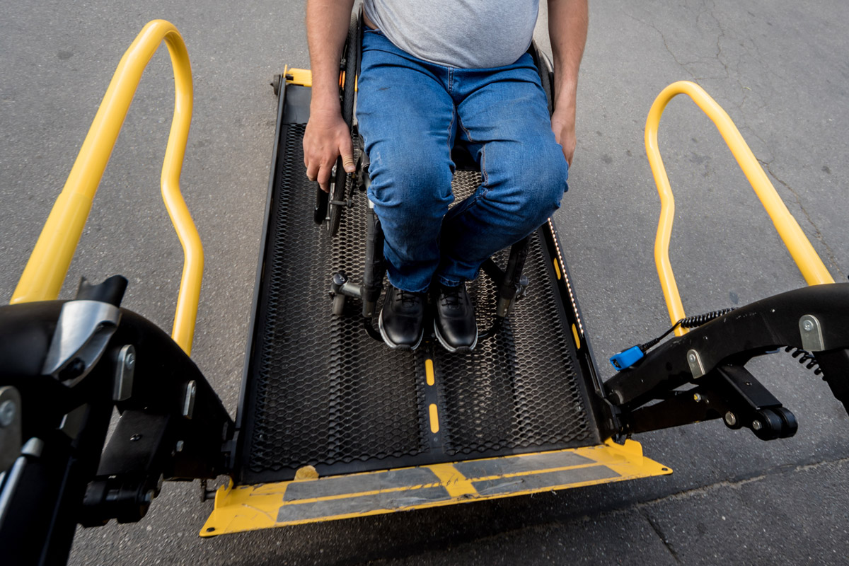 A man uses a chair lift to get into his van since he's in a wheelchair.