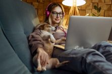 A woman works from home with her small dog sleeping on her.