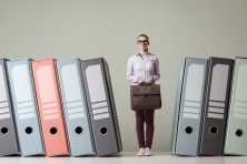 An employee stands between giant binders.