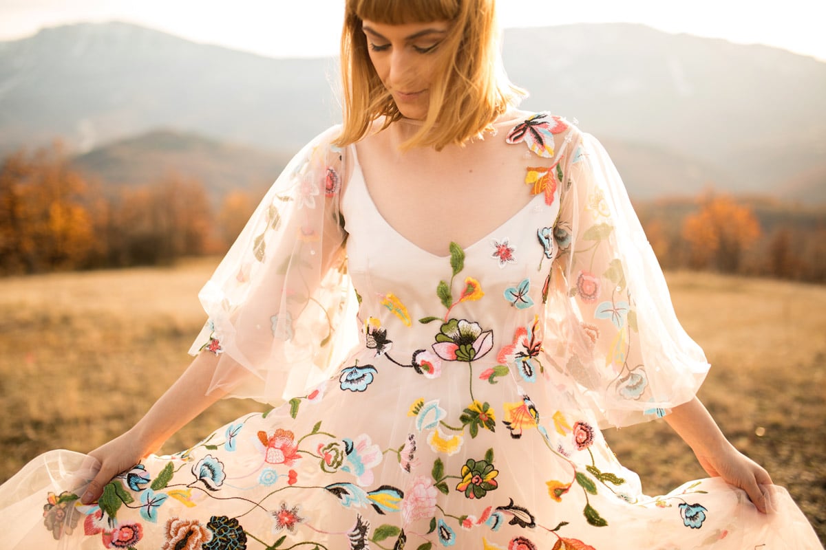 A woman wears a wedding dress in a field.