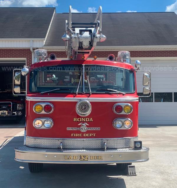 A fire truck sits outside of a fire house. 