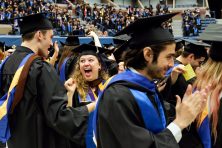 Graduates cheer in excitement during their college graduation ceremony.