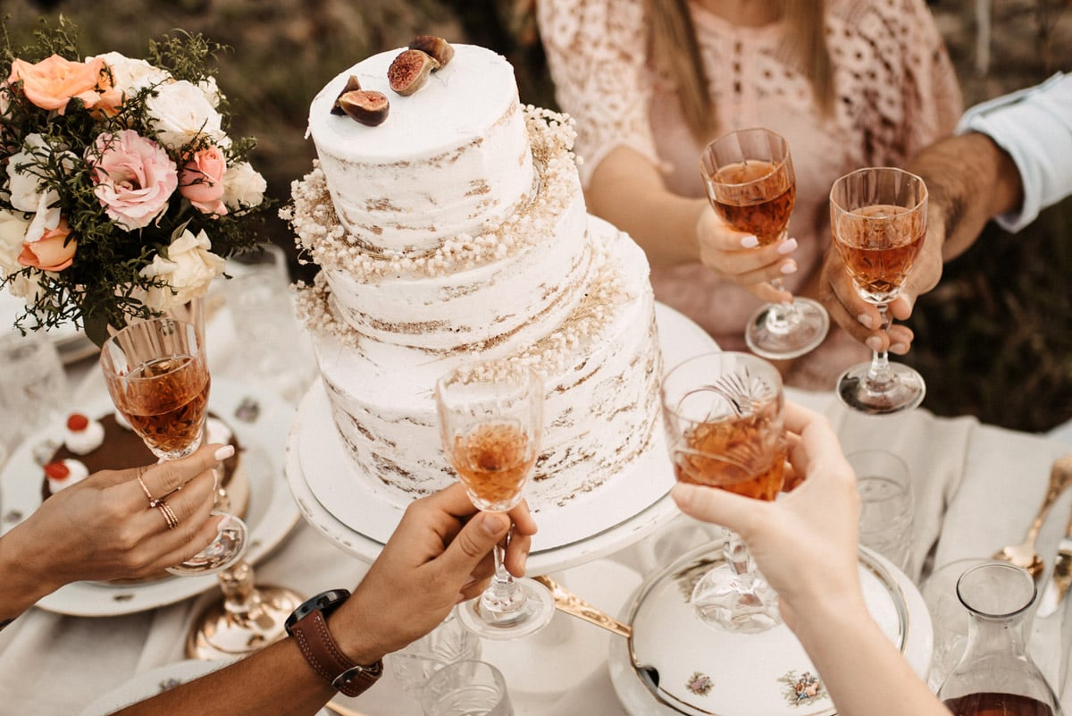 People cheers near a wedding cake. 