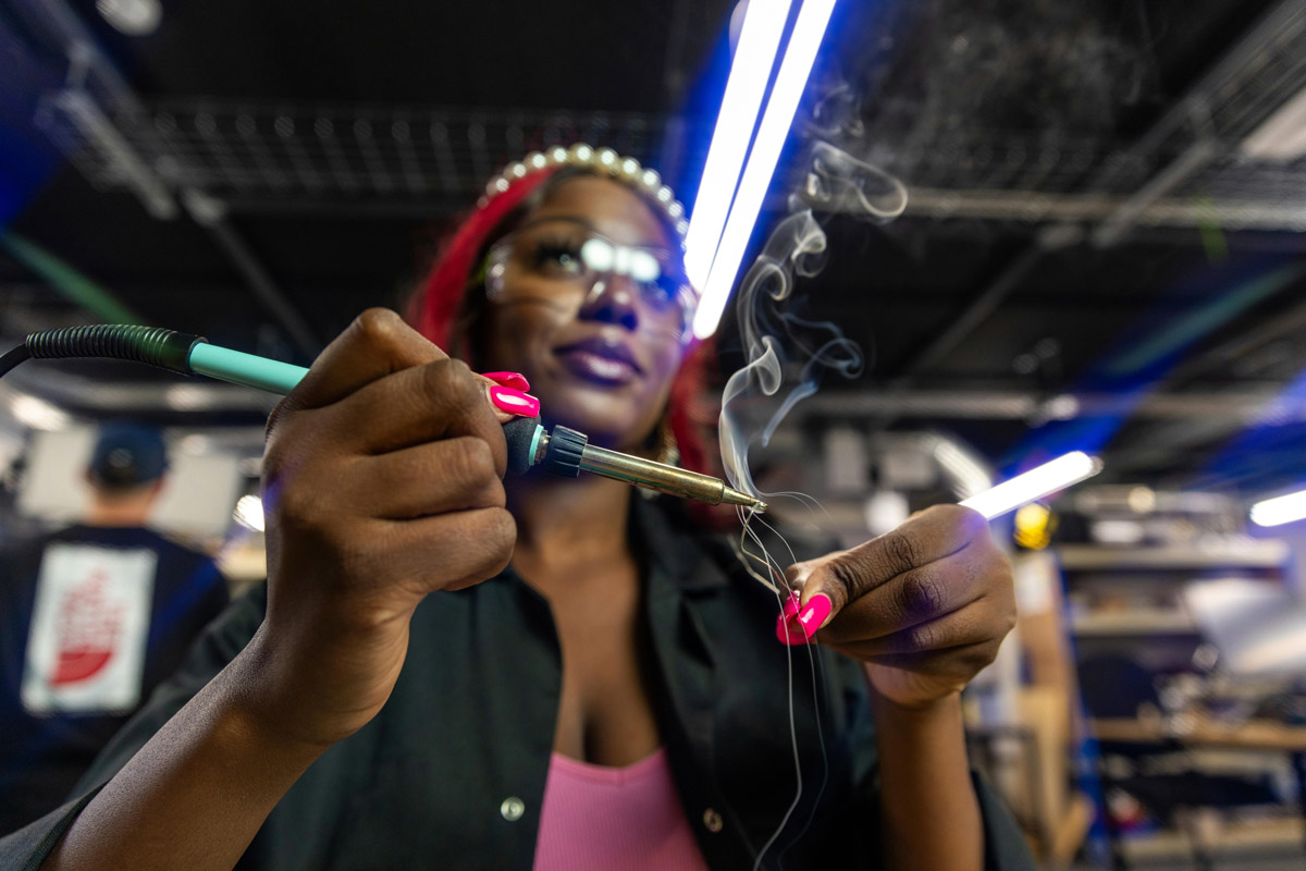 A woman uses a welding torch. 