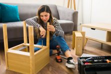 A woman puts together a side table in the living room.