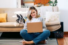 A woman works from home with her dog sitting next to her.