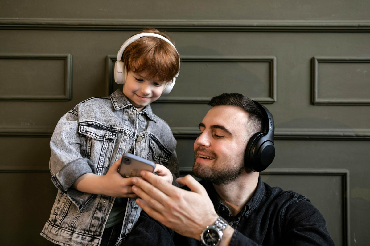 A father and son listen to something on the phone. 