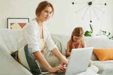 Single parent reviewing their family budget on a laptop while managing household tasks