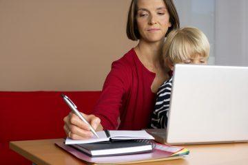 Single parent reviewing household finances on a laptop while managing family life