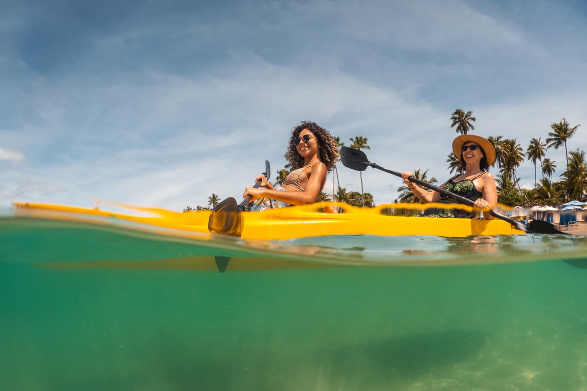 Two women kayak in the ocean.