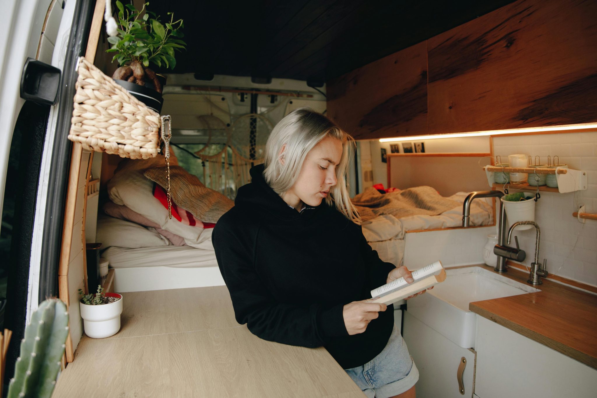 A woman reads a book in a tiny home, which is an alternative housing option.