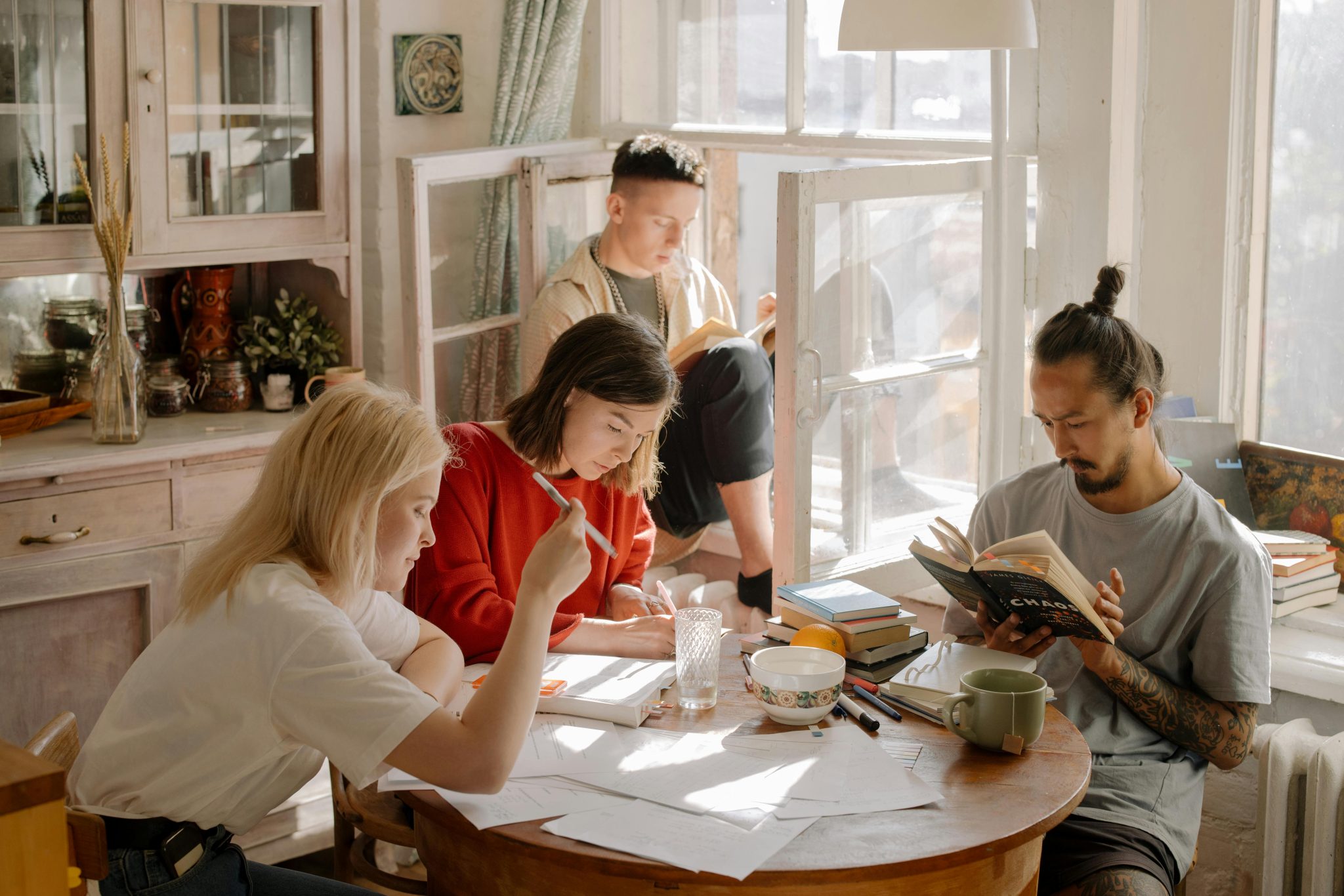 A group of young people sit in a kitchen together. Co-living is an alternative housing option.