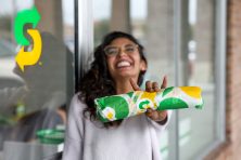 A woman smiles with a sub from subway in her hand.