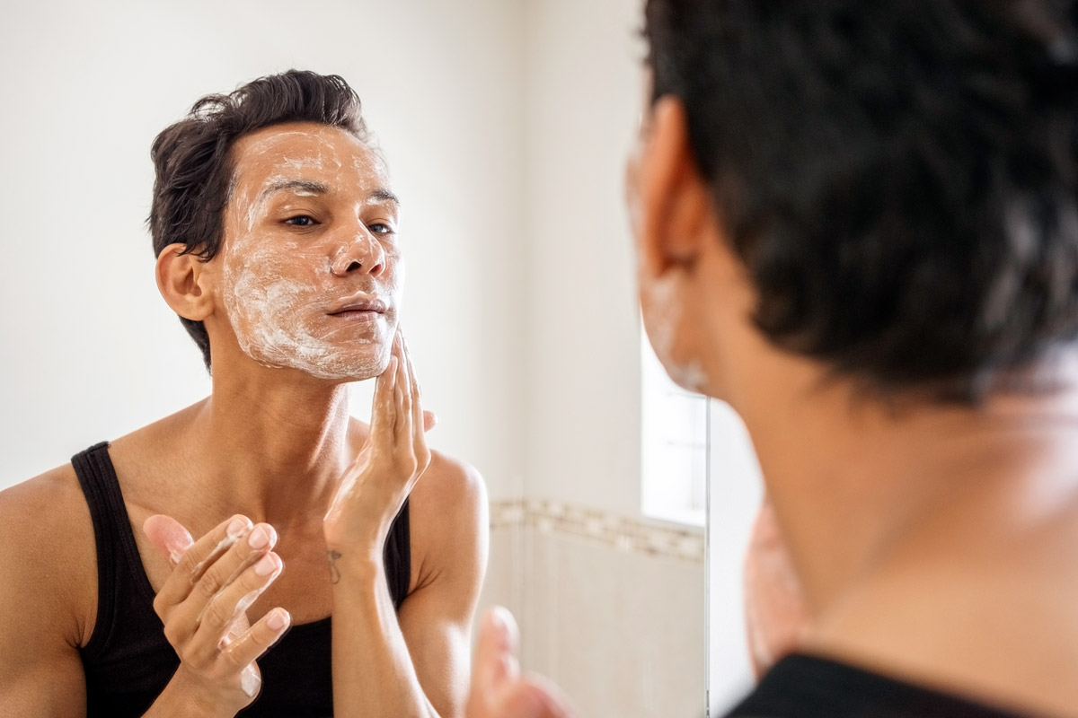 A man washes his face in the bathroom. 